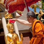 The monk of Buddha Raleigh Temple in Kings Mountain, NC, offers a water blessing to a Prabang Buddha at the 2016 Pii Mai (Lao New Year) celebration.